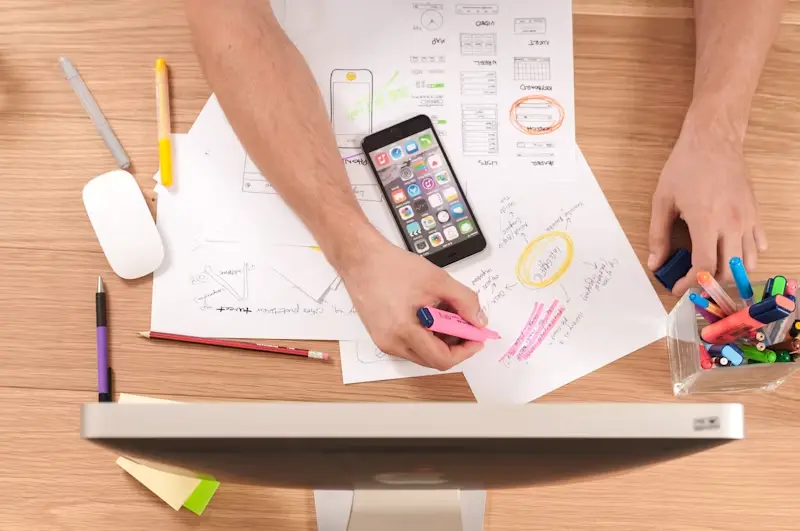 Designer creating a mobile app wireframe and user interface layout on a desk with smartphone and design sketches,Google Seo Services
